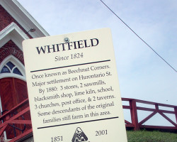 A historical sign, erected in front of the church in 2001, marks the location of the former community of Whitfield. Photo of sign